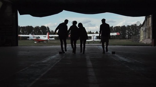 Slow motion of group of people walking through hangar and then leaving it.