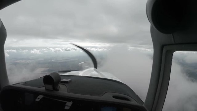 View from a small plane of grey storm clouds over an open landscape below in a concept of flying and aviation