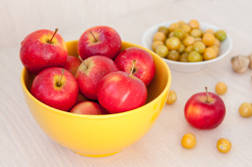 On table cup of red apples and green berries