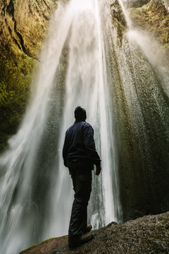Hiker Looking Up at the top of Glufrafoss Hidden Waterfall