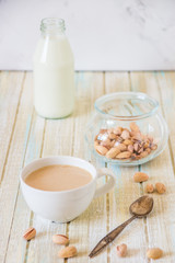Coffee with milk and pistachios on wooden table