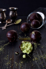 Healthy raw energy bites with coconut, avocado and tea matcha. Vegan chocolate truffles on dark wooden background. Homemade candy. Copy space
