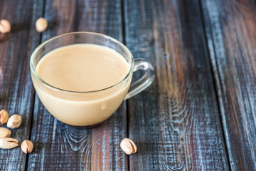Obraz na płótnie Canvas Coffee with milk and pistachios on the table, copy space