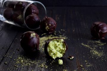 Healthy raw energy bites with coconut, avocado and tea matcha. Vegan chocolate truffles on dark wooden background. Homemade candy. Copy space