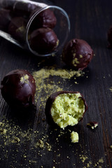 Healthy raw energy bites with coconut, avocado and tea matcha. Vegan chocolate truffles on dark wooden background. Homemade candy. Copy space