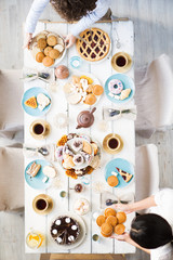 Top view of festive table and two females serving it for guests