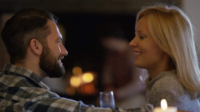  Portrait romantic smiling couple relaxing with wine in front of open fire