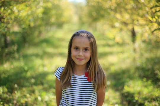 A Pretty Girl Smiles In A Sunny Autumn Apple Orchard