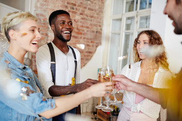 Two young ecstatic couples toasting with champagne while celebrating anniversary of their friendship