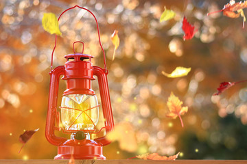 Autumn leaves blowing in the wind across a burning lantern
