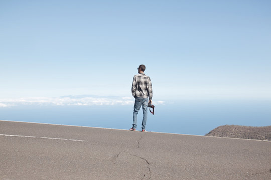 Young man standing in the street and watching the ocean