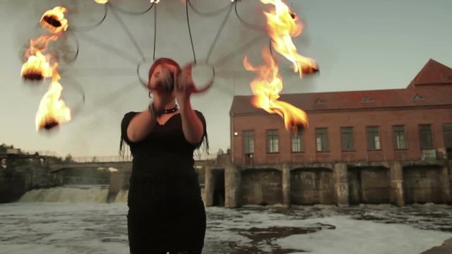 A young girl shows a fire show against the backdrop of an old German hydroelectric power station.
