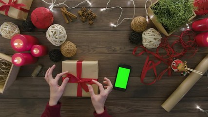Top view hands tie a bow using digital tablet at wooden desk from above with christmass decoration - Powered by Adobe