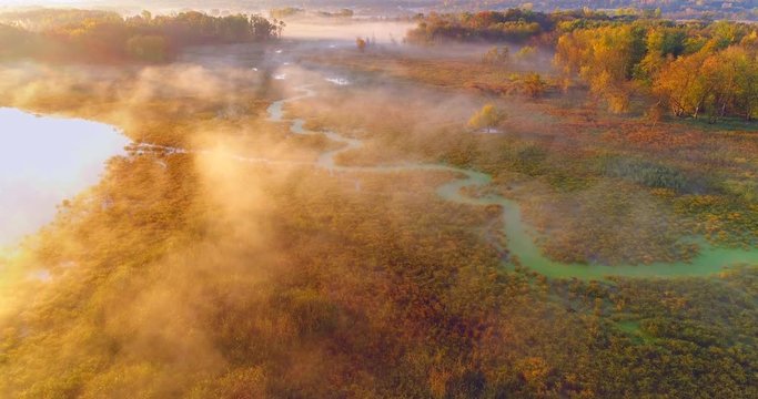 Aerial view of breathtaking foggy wilderness at dawn, with winding river, Autumn colors.