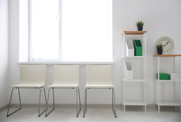 Modern room interior with white chairs and shelving unit