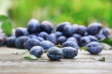 Tasty ripe plums on wooden table outdoors