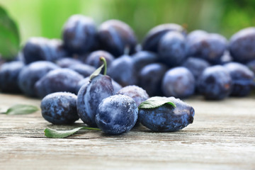Tasty ripe plums on wooden table outdoors