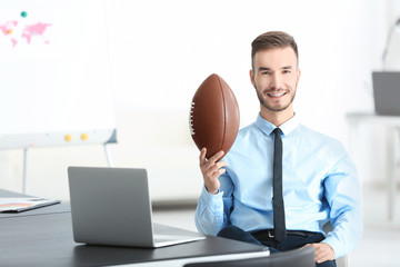 Young handsome man with ball for American football in office © Africa Studio