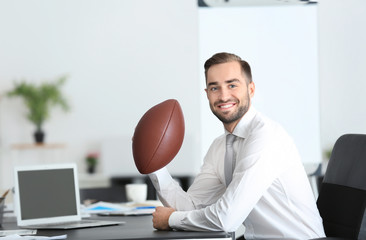 Young handsome man with ball for American football in office © Africa Studio