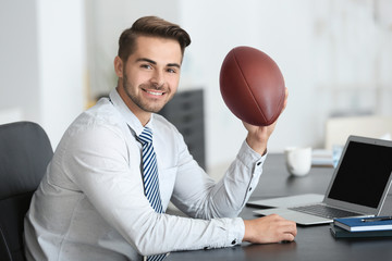 Young handsome man with ball for American football in office © Africa Studio