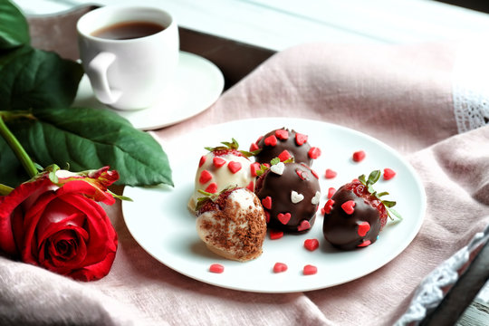 Tray with tasty glazed strawberries, cup of tea and beautiful flower, closeup