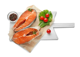 Wooden board with fresh salmon steaks on white background