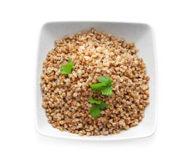 Bowl with cooked buckwheat on white background