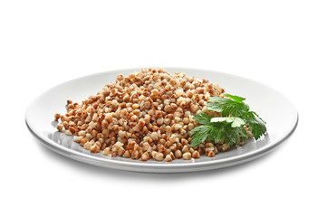 Plate with cooked buckwheat on white background