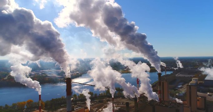 Industrial smokestacks, billowing emissions of smoke or steam, stunning aerial view.
