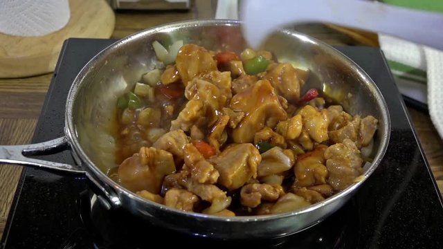 Stirring Kung Pao chicken in a skillet
