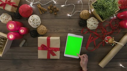 Top view hands tie a bow using digital tablet at wooden desk from above with christmass decoration - Powered by Adobe