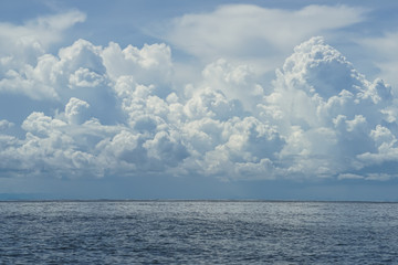 Dramatic scene of powerful white cloud, shades of blue sky background and deep blue sea with ocean water ripple