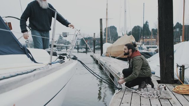  Father & son mooring sailing boat to the dock in a marina