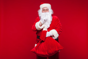 Christmas. santa claus with big bag on shoulder is on red background