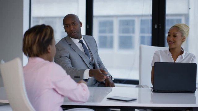 Business managers interviewing potential employee and shaking hands at end of meeting.