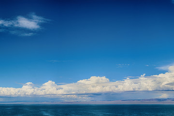 sunbeams reflecting on mirror water surface of sea with dark fluffy clouds on sky 
