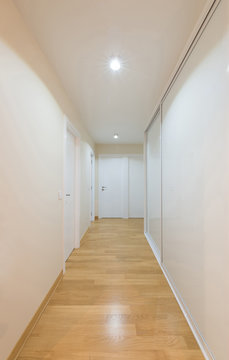 Interior of a white corridor with sliding door closet and wooden parquet