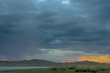 sunbeams reflecting on mirror water surface of sea with dark fluffy clouds on sky 
