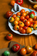 Fresh organic tomatoes of different colors on mustard yellow textile background. Harvest concept. Overhead view, natural lighting.