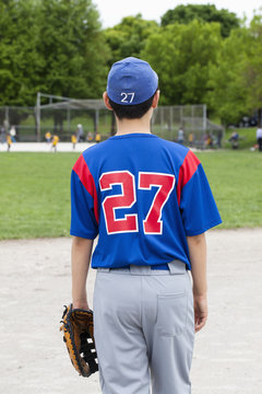 Rear view of teenage boy in baseball uniform at ballpark