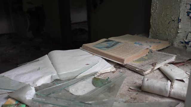 Chernobyl, Ukraine - 17th of June 2017: Visit to Zalesye village in Chernobyl zone - 4K Books in Russian on window sill in abandoned village house