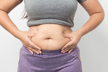 Overweight woman hand pinching excessive belly fat on gray background, Healthy concept