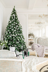 Christmas morning. classic apartments with a white fireplace, decorated tree, bright sofa, large windows
