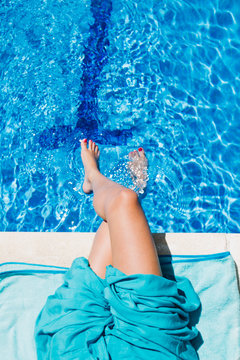 Young woman??s legs into a swimming pool during a summer day