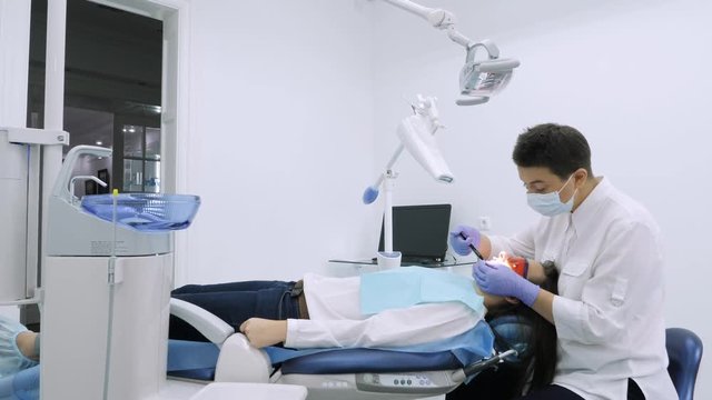 The dentist preparing patient for teeth whitening procedure