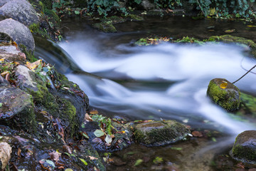 long exposure photo of a small waterfall falling down the stream