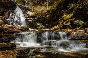 Fototapeta na wymiar Waterfalls are surrounded by colorful fall foliage at Ricketts Glen State Park in Benton, PA