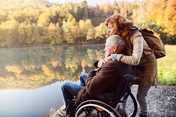 Senior couple with wheelchair in autumn nature.