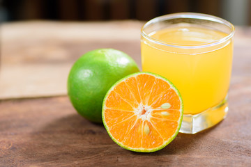 Green tangerine orange fruit and juice on wooden background, healthy food