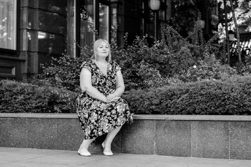 Happy overweight woman walking the city street at good day. Sunny portrait of size plus lady. Beautiful overweight woman standing on city street